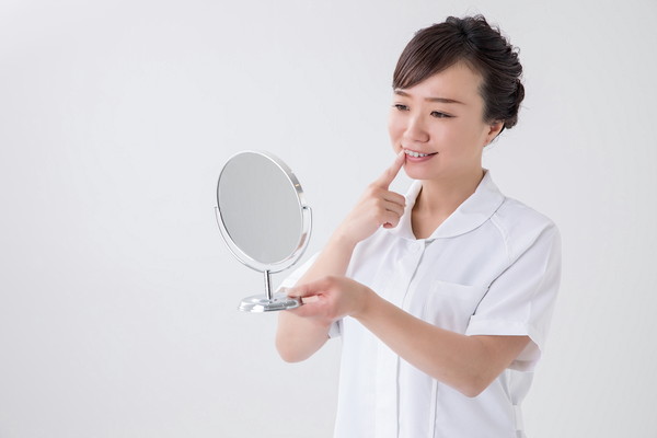 鏡で歯を確認する女性