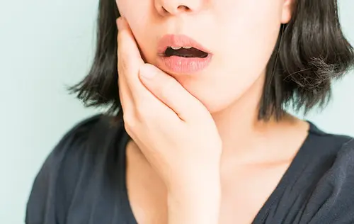 歯の痛みで頬を押さえる女性
