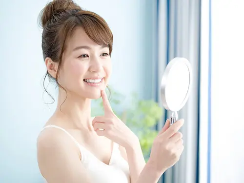 鏡で歯を確認する女性
